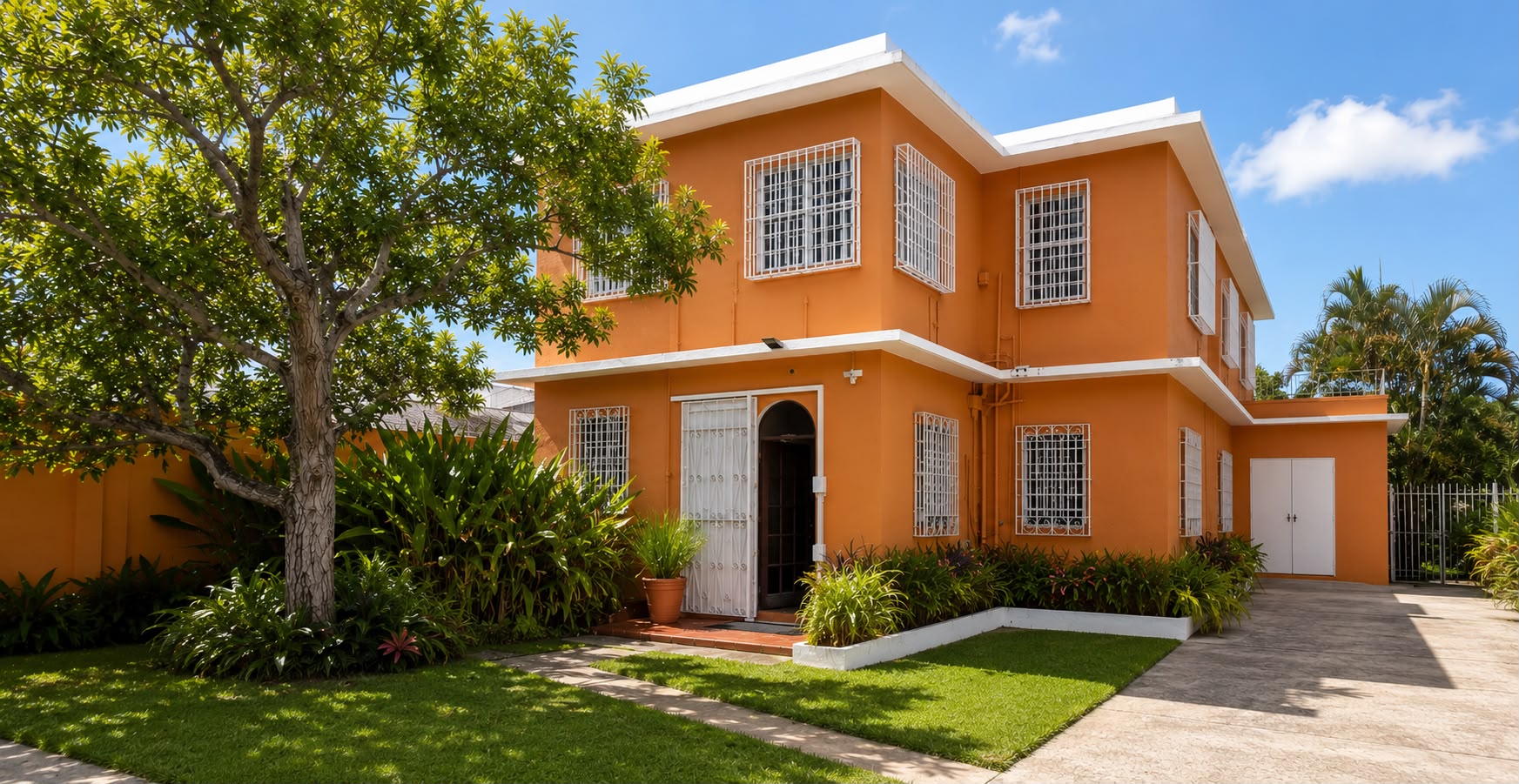 La Casita, parte de La Casona, casa de dos plantas color naranja con jardines y árbol al frente